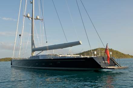 A majestic yacht named MYSTERY cruises through calm turquoise waters under a clear blue sky.