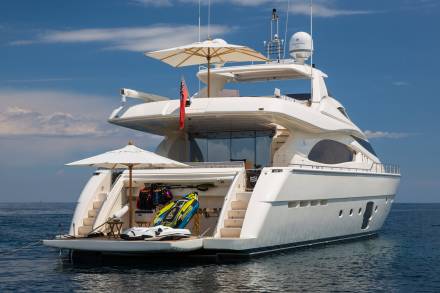 A luxurious white yacht floats serenely on the deep blue sea, its deck adorned with water toys and umbrellas.