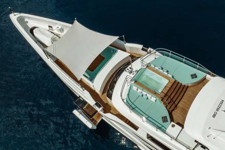 A luxurious white yacht with turquoise seating and a hot tub glides through deep blue waters.