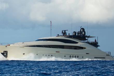 A sleek, modern yacht cuts through the deep blue ocean, leaving a powerful wake in its path.