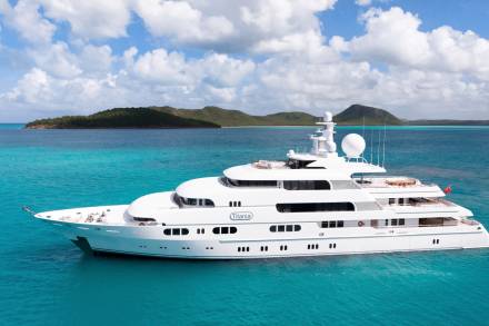 The luxurious superyacht Titania glides through the crystal-clear turquoise waters of a tropical paradise.