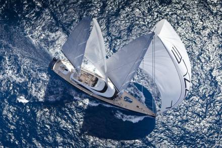 A majestic sailing yacht cuts through the deep blue ocean, its sails billowing gracefully in the wind.