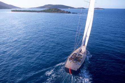 A majestic sailboat glides through the deep blue ocean, with lush islands dotting the horizon.