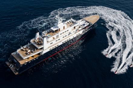 Jet skis create frothy trails behind a luxurious yacht cruising through the deep blue ocean.