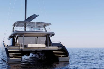 A sleek, modern catamaran yacht named Nalani glides across the calm, blue ocean under a clear sky.