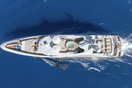 A luxurious yacht glides through the deep blue ocean, its deck featuring a relaxing hot tub and ample space for sunbathing.