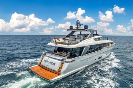 A luxurious San Lorenzo yacht glides through the deep blue ocean under a bright, cloud-dotted sky.