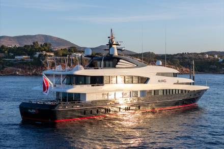 The luxurious yacht Alfa G glides through calm waters under a clear sky, reflecting the golden sunlight.