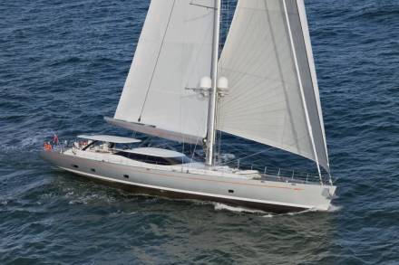 A sleek, modern sailboat glides through the deep blue ocean, its white sails billowing in the wind.