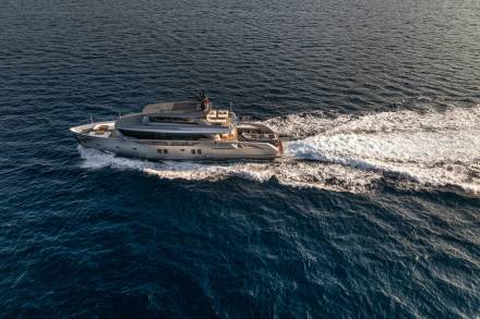 A sleek, modern yacht glides through the deep blue ocean, leaving a foamy white wake in its path.