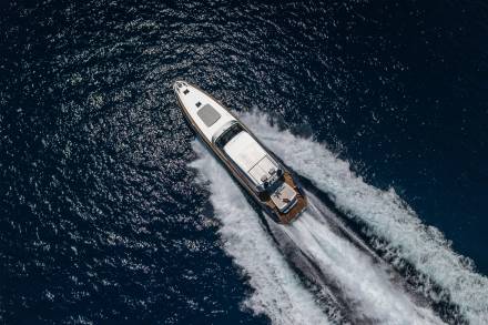 A sleek white yacht cuts through the dark, sparkling ocean, leaving a dramatic white wake in its powerful wake.