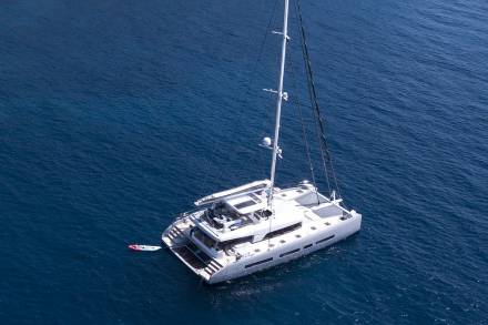 A white catamaran sailboat floating on the deep blue ocean waters.