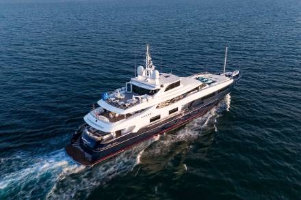 A luxurious superyacht glides through the deep blue ocean, leaving a trail of white wake.