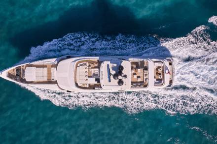 A large white yacht is seen floating on the deep blue waters, surrounded by a stunning mountainous landscape in the background.