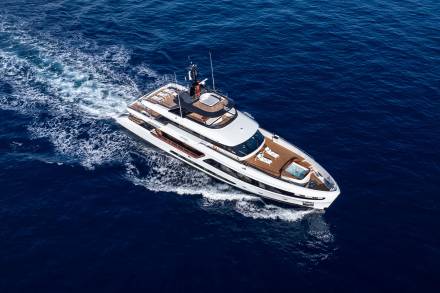 A large, luxurious yacht cruising across the deep blue waters of the ocean, leaving a trail of white foam in its wake.