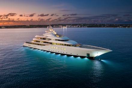 A luxurious superyacht glows with underwater lights in the tranquil waters at sunset.
