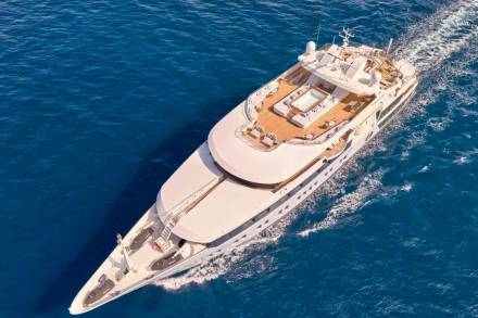 A luxurious white yacht glides through the deep blue ocean, leaving a foamy wake behind.