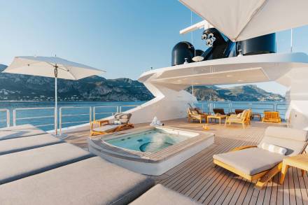 Relax on the spacious deck of a luxury yacht, complete with a hot tub, sun loungers, and stunning coastal views.