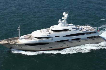 A sleek, modern superyacht glides through the deep blue ocean, leaving a white wake in its powerful path.
