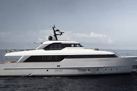 A large, sleek white yacht floating on the calm, blue ocean with a clear sky in the background.