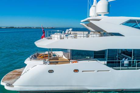 A luxurious white yacht glides through turquoise waters under a clear blue sky.
