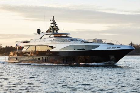 The sleek yacht "Ghost" glides through calm waters under a soft, cloudy sky.