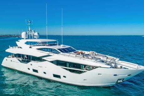 A sleek white yacht glides across the azure waters under a clear blue sky.