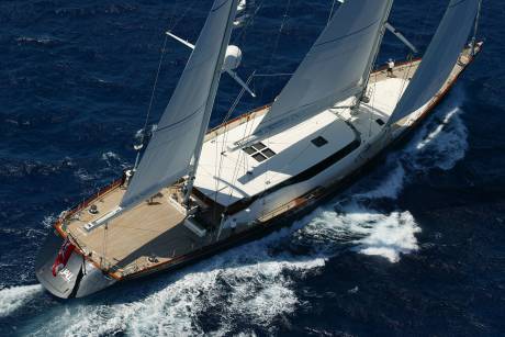A majestic sailing yacht glides through the deep blue ocean, its sails billowing in the wind.