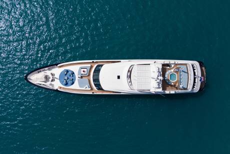 A luxurious yacht with a jacuzzi and lounge area floats serenely on the deep blue ocean.