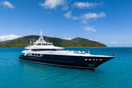 A luxurious yacht named Mischief floats serenely on the turquoise waters of a tropical bay.