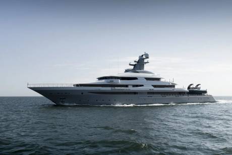 A sleek, gray superyacht cruises on calm, dark blue water under a pale, hazy sky.