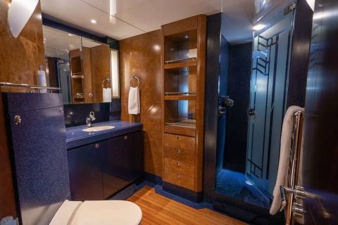 A modern and well-designed bathroom with wooden cabinets, a blue vanity, and a mirror on the wall.