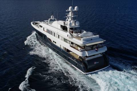 A large, luxurious white yacht sailing across the deep blue ocean, leaving a trail of white foam in its wake.
