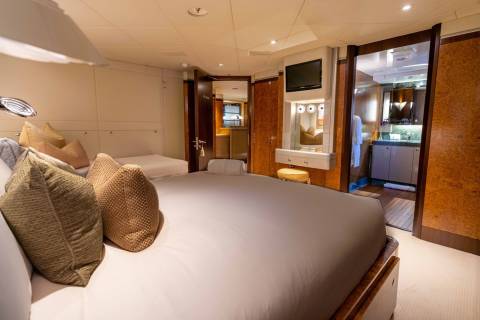 A cozy and well-appointed bedroom with a large bed, wooden accents, and a bathroom visible in the background.