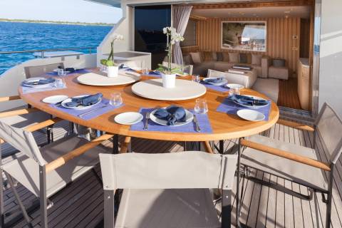 Dine al fresco on a luxurious yacht deck, surrounded by the azure sea and elegant interior living spaces.