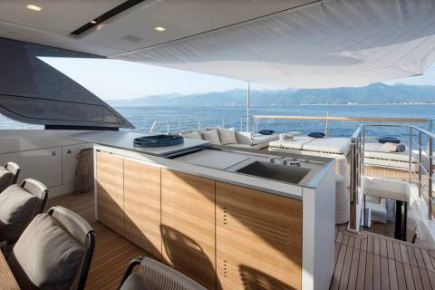 Luxurious yacht deck features a modern outdoor kitchen and comfortable lounge area with stunning ocean views.