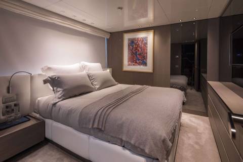 A luxurious yacht bedroom features a plush bed, modern art, and mirrored wardrobes for a sophisticated retreat.