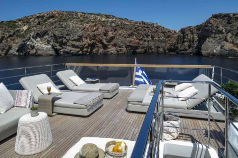 Relax on the sun-drenched deck of a luxury yacht, surrounded by the stunning natural beauty of the Greek islands.
