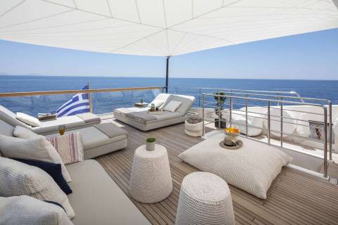 Relax on the luxurious deck of a yacht, enjoying the serene blue ocean and a refreshing drink.