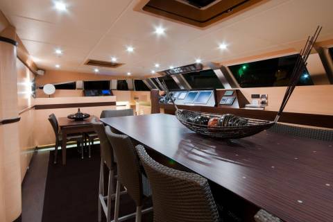 Luxurious yacht interiors feature a spacious dining area with a polished wooden table and comfortable seating.