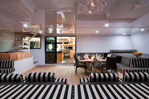 Elegant striped seating and a dining area create a sophisticated outdoor lounge on this luxurious yacht.