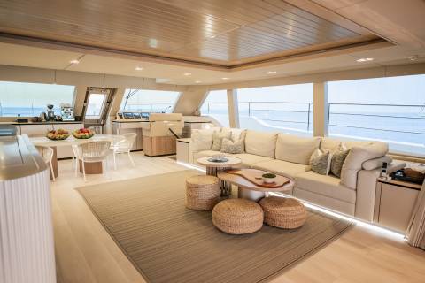 A spacious yacht salon offers a comfortable seating area with a view of the ocean through large windows.