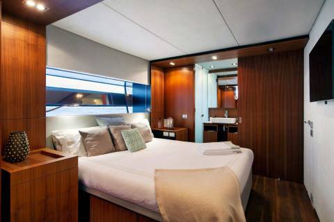 Luxurious yacht cabin features a plush bed, elegant wood accents, and a sleek en-suite bathroom.