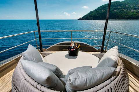 Relax in luxurious comfort on this yacht's deck, surrounded by plush cushions and chilled champagne, with a stunning ocean view.