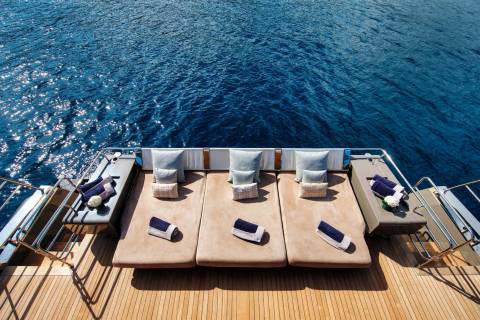 Relax on plush loungers with rolled towels and decorative pillows, overlooking the sparkling blue ocean.
