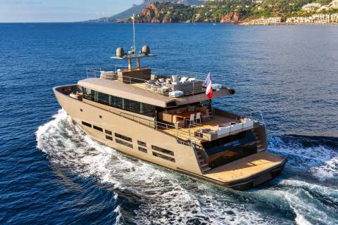 A sleek, modern yacht glides through the azure waters of the Mediterranean, leaving a foamy wake behind.