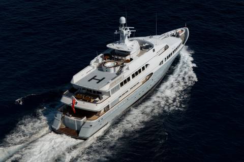 A luxurious yacht cruises through the deep blue ocean, leaving a frothy white wake behind it.