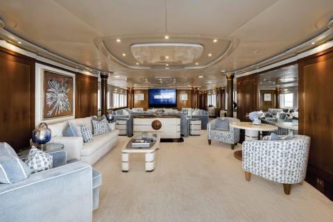 Luxurious yacht interiors feature plush seating, elegant artwork, and a large screen for entertainment.