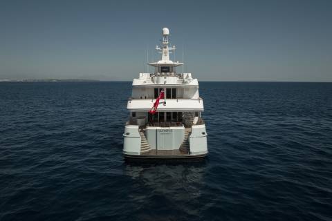 The majestic yacht Olympus glides serenely across the deep blue sea under a clear sky.