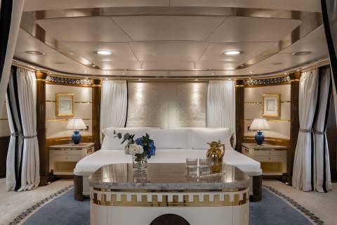 Luxurious gold accents and plush white linens adorn this opulent yacht stateroom.